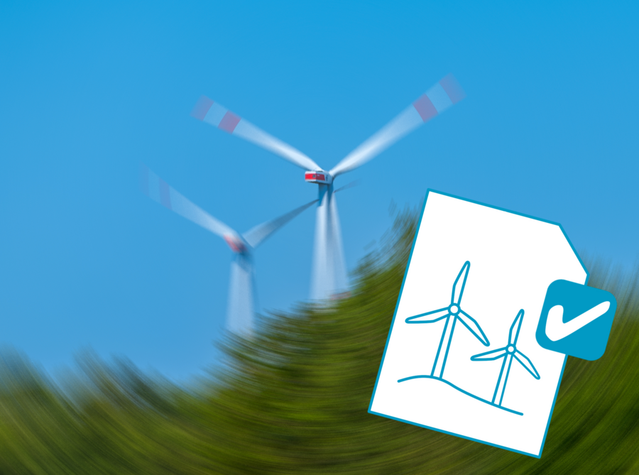 Windräder verschwommen im Hintergrund, Papier mit Zeichnungen von Windrädern im Vordergrund 