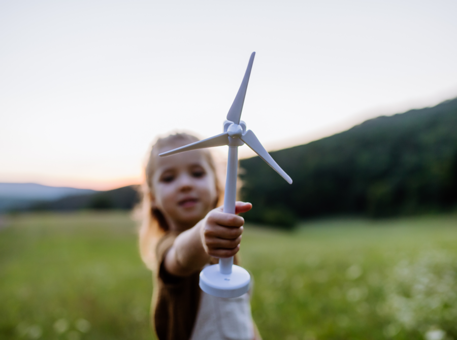 Ein kleines Mädchen hält ein kleines Windrad in die Kamera