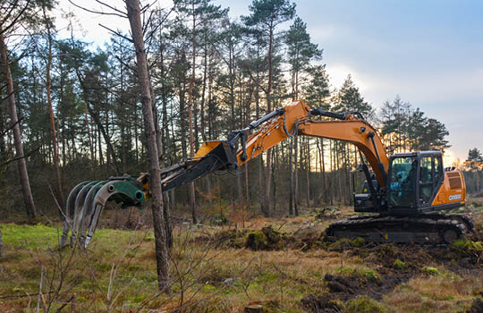 Orangener Bagger vor einem Wald 
